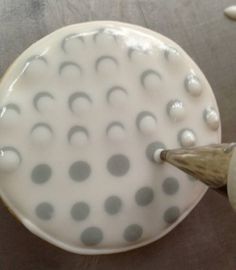 a white plate with black dots on it being held by a person's hand