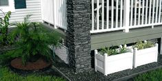 a porch with white railings and planters on the front lawn in front of a house