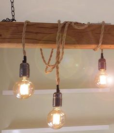 three light bulbs hanging from a beam with rope on it's ends and two lights in the middle