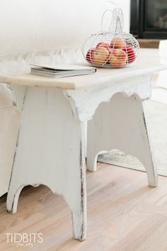 a white table with apples on it in front of a couch