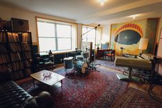 a living room filled with lots of furniture and musical instruments on top of a rug