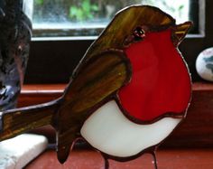 a red and white bird sitting on top of a window sill