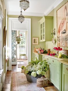 a kitchen with green cabinets and flowers in a pot on the counter next to an open door