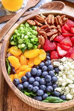 a wooden bowl filled with fruit and nuts