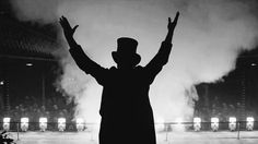 a man standing in front of a stage with his arms up and hands raised to the sky