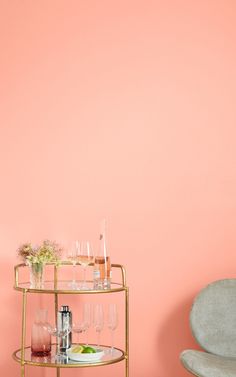 a bar cart with drinks on it against a pink wall