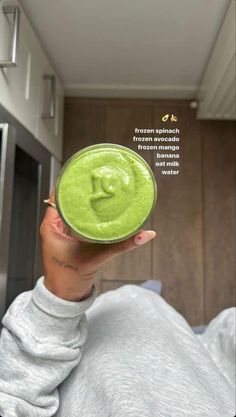 a woman holding up a green smoothie in front of her face