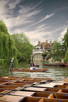 two people in rowboats paddling down a river with houses on the other side