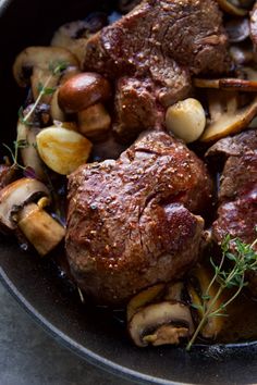 a pan filled with meat and mushrooms on top of a table