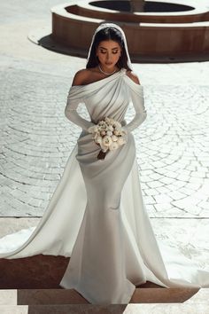 a woman in a white wedding dress standing on steps with her hands on her hips