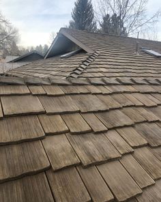 the roof of an old house with wood shingles on it's sides and trees in the background