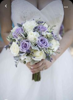 a bride holding a bouquet of white and purple flowers