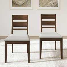 two wooden chairs sitting next to each other in a room