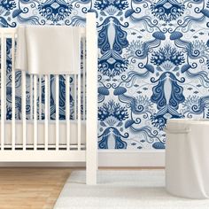 a white crib in front of a blue and white wallpaper