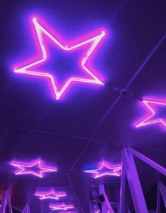 purple and pink stars hanging from the ceiling in a room with other lights on it