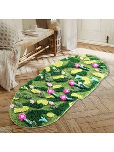 a green rug with pink and yellow flowers on it in the middle of a wooden floor