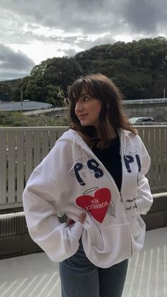 a woman standing in front of a fence with her hands on her hips