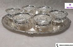 an ornate silver tray with six glass dishes on it