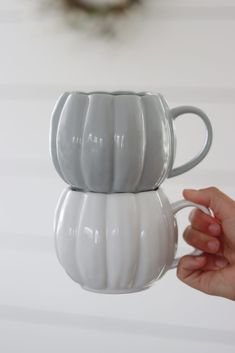 two white coffee mugs sitting on top of each other