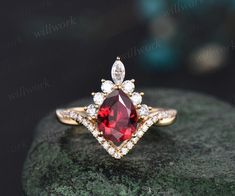 a red and white diamond ring sitting on top of a rock