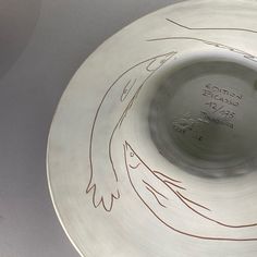 a silver plate with writing on it and an orange bird drawn on the side in red ink