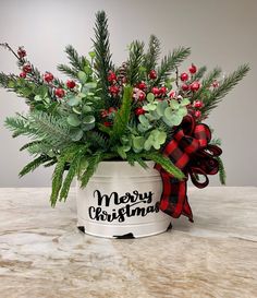 a christmas planter with red berries and greenery in it sitting on a table