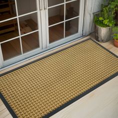 a door mat sitting on top of a wooden floor next to a potted plant