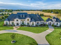 an aerial view of a large home in the middle of a green field with lots of trees