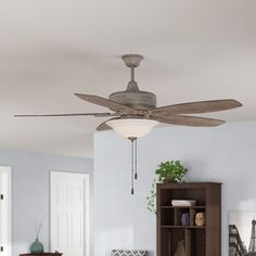 a ceiling fan in a living room next to a book shelf and bookshelf