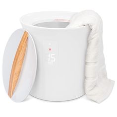 a white electric waxing machine next to a wooden spoon and towel on a white background