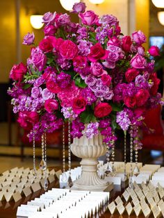 a vase filled with pink flowers on top of a table next to cards and place names