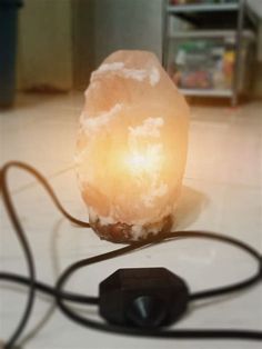 a rock lamp sitting on top of a white tiled floor next to a black cord