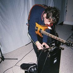 a young man playing an electric guitar in front of a recording equipment set up on the floor