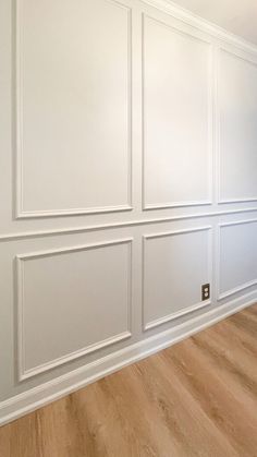 an empty room with white paneling and wood floors