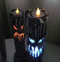 two candles that have been made to look like they are decorated with glowing eyes and fangs