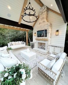 an outdoor living area with white furniture and a fireplace