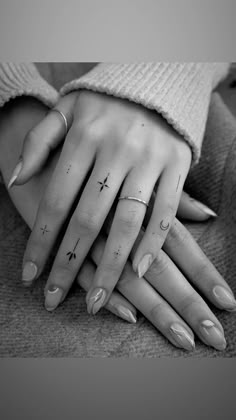 two hands holding each other with tattoos on their fingers and one has a cross tattoo on it