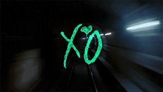 a green xo sign on the side of a train track at night with motion blur