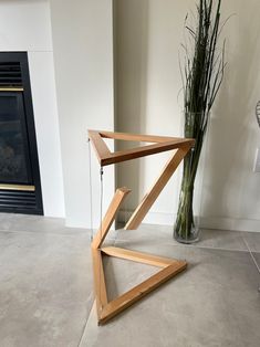 a vase with some flowers in it next to a wooden structure that has been placed on the floor