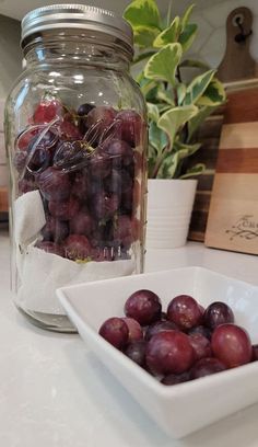 grapes are in a bowl next to a mason jar