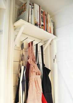 a shelf with clothes hanging on it next to a book case and bookshelf