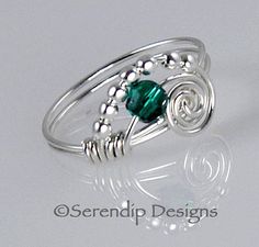 a silver ring with a green stone in the center and beaded wire around it