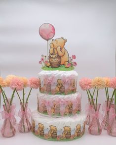 there is a three tiered cake with teddy bears on it and pink flowers in vases