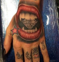 a person's hand with a tattoo on it and a diamond in the mouth