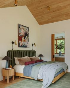 a bedroom with a bed, nightstands and paintings on the wall