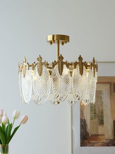 a chandelier hanging from the ceiling with flowers in vases next to it