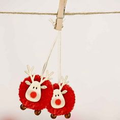 two red and white reindeer ornaments hanging from a line with clothes pins attached to them