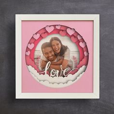 a pink and white photo frame with the word love on it, surrounded by hearts