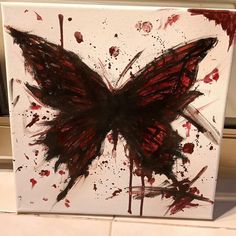 a painting of a butterfly with red and black paint splattered on it