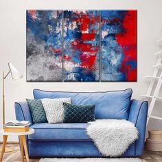 a living room with a blue couch and three paintings on the wall